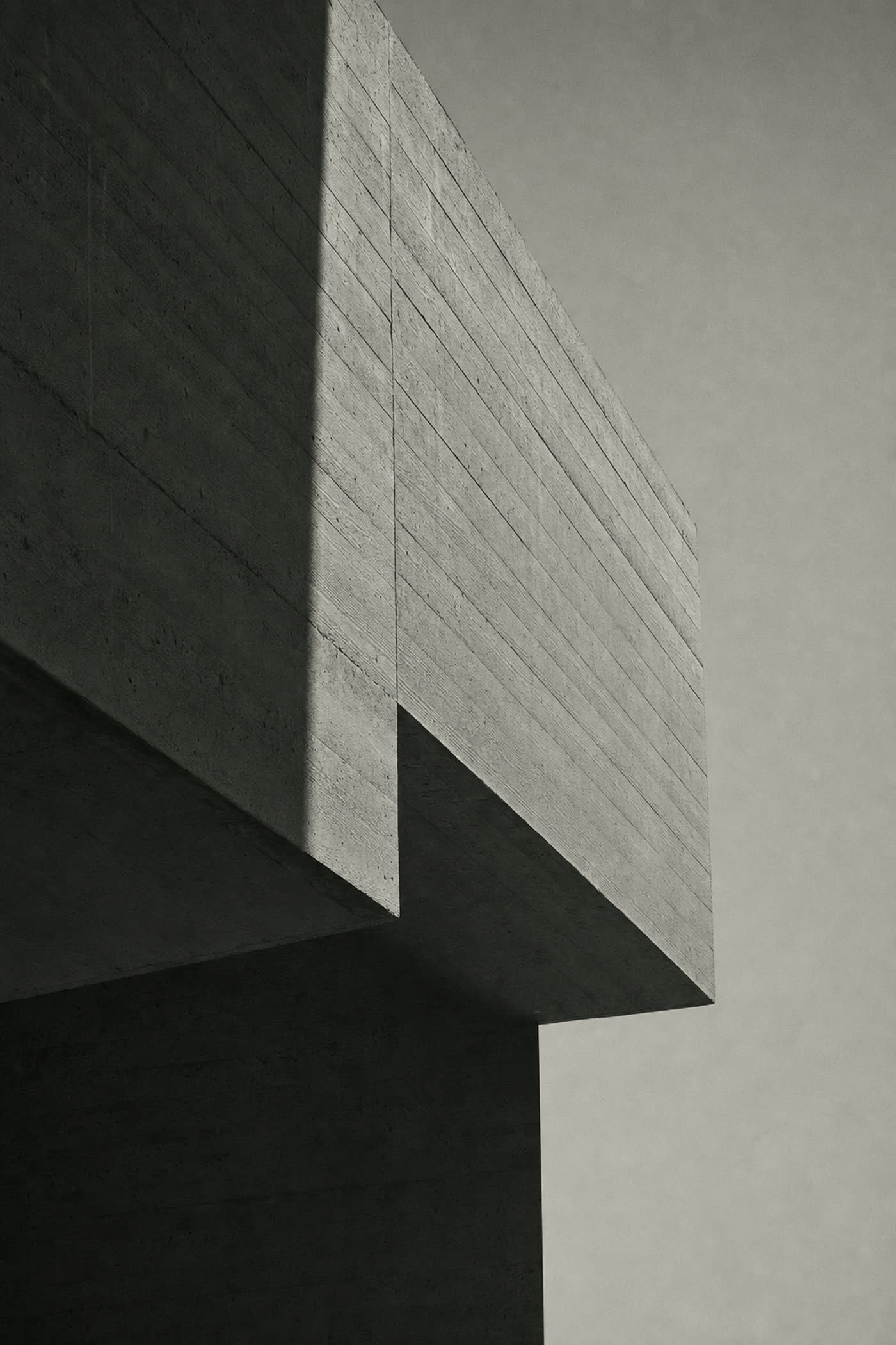 Abstract monochrome architectural study: light falling across a board-formed concrete edge